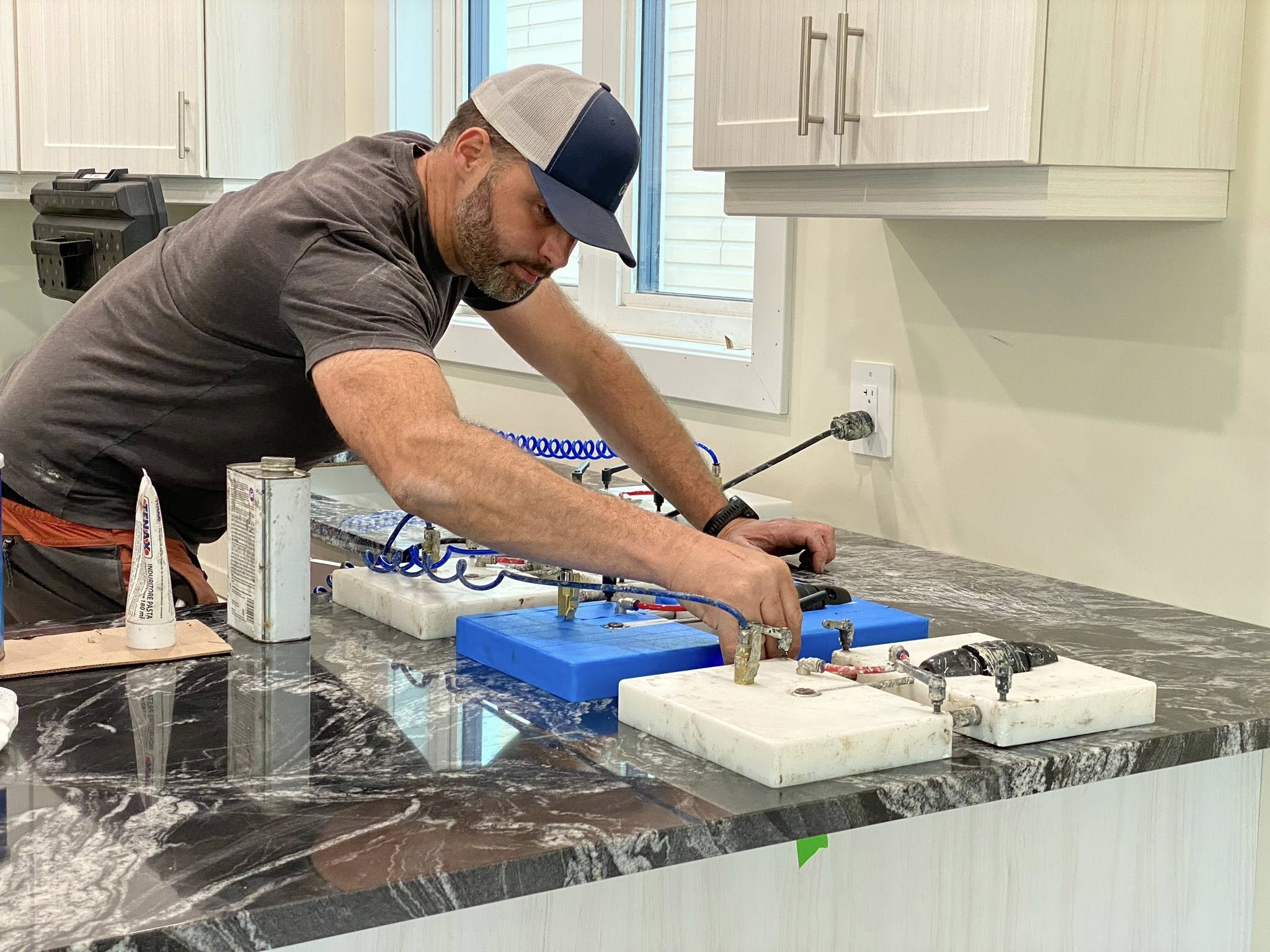 Infinity Yukon installer drilling on a black granite countertop during install day.
