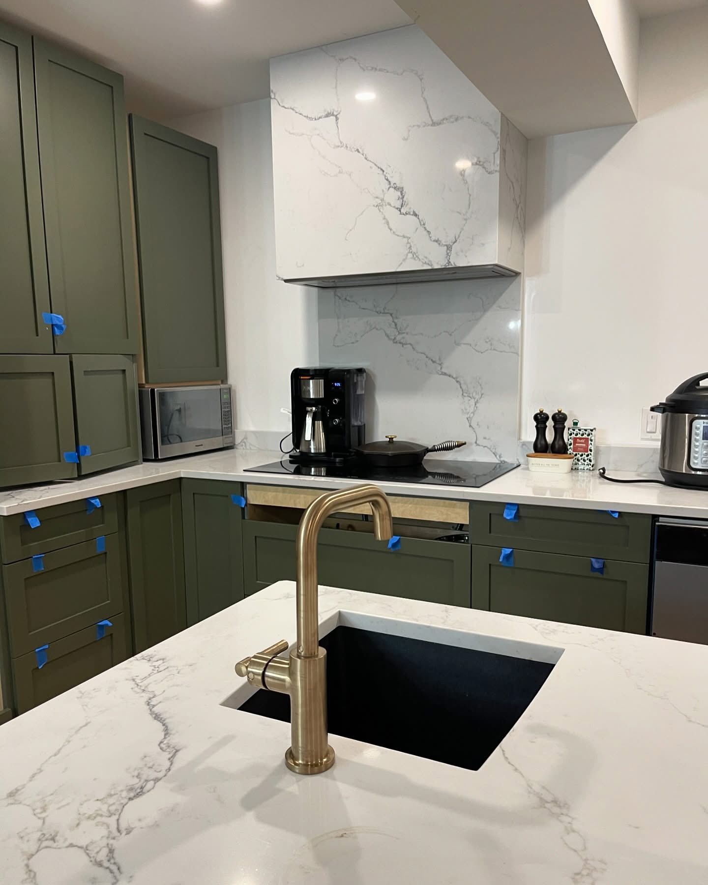 Sage green shaker kitchen with white Calacatta-look quartz waterfall island and brass fixtures.